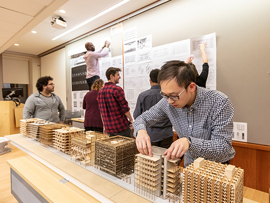 group of students discussing thesis posters on the wall