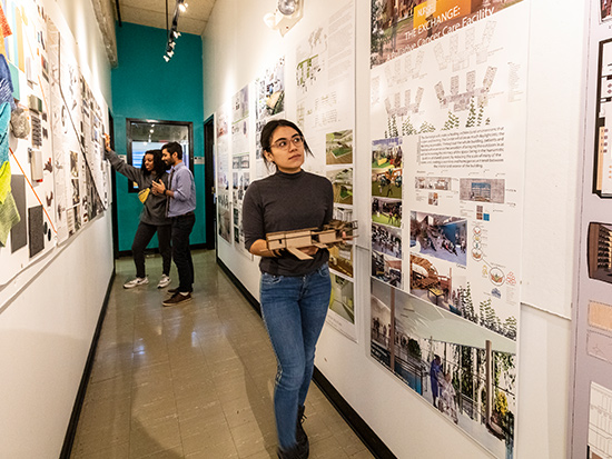 girl walking by a wall of thesis posters