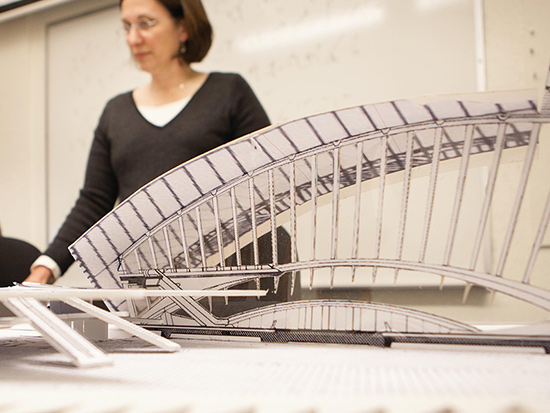 woman lecturing in front of architecture model